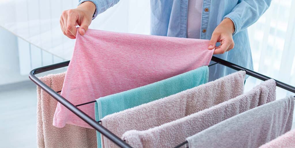 Woman hangs towels to dry on rack.