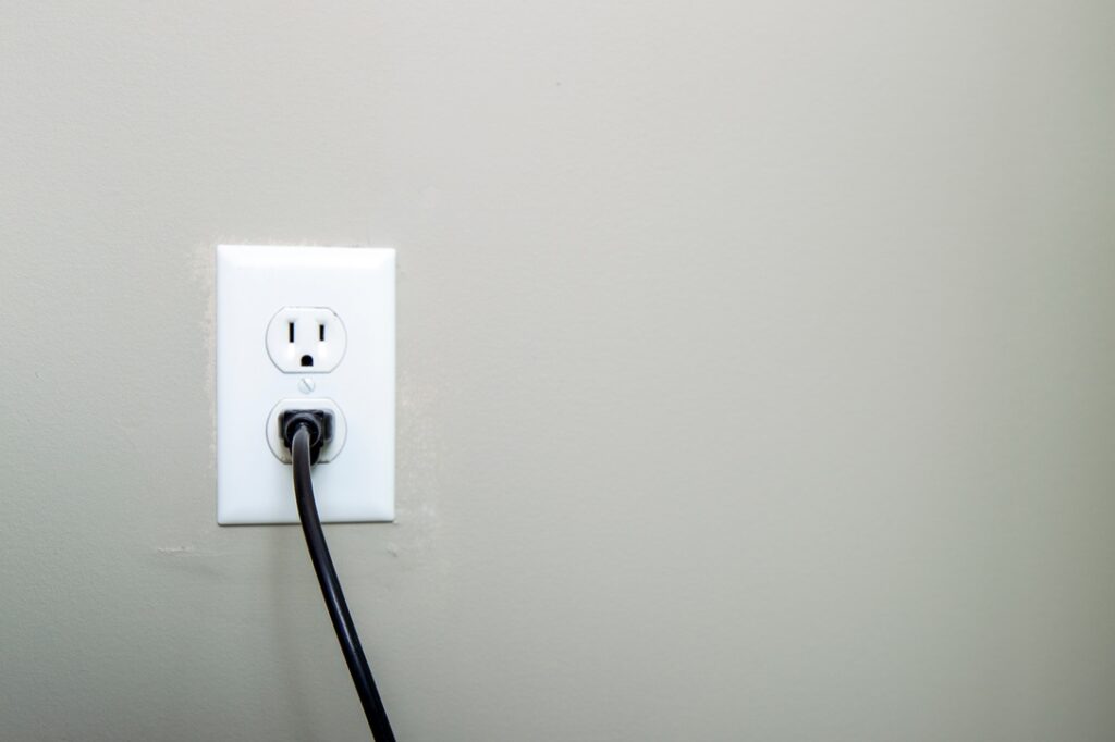 Black cord plugged into a white outlet