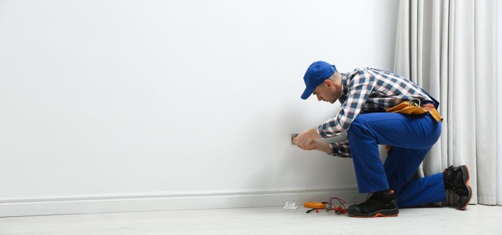 Professional electrician repairing power socket in room