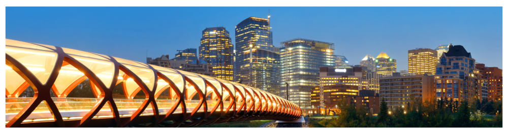 Calgary cityscape at night, showcasing the illuminated Peace Bridge and downtown skyscrapers in Alberta, Canada.