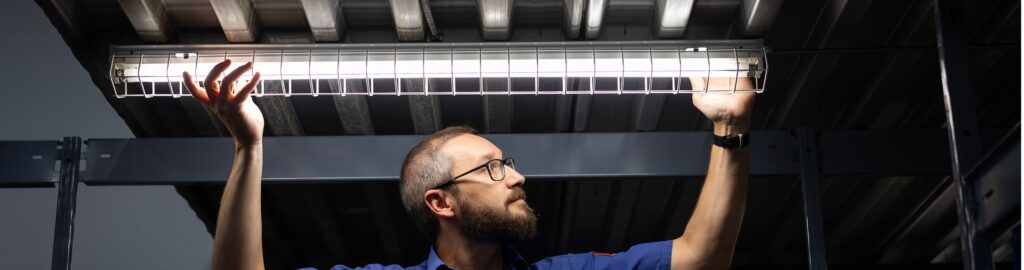A 4 Star technician installing a light in a commercial warehouse.