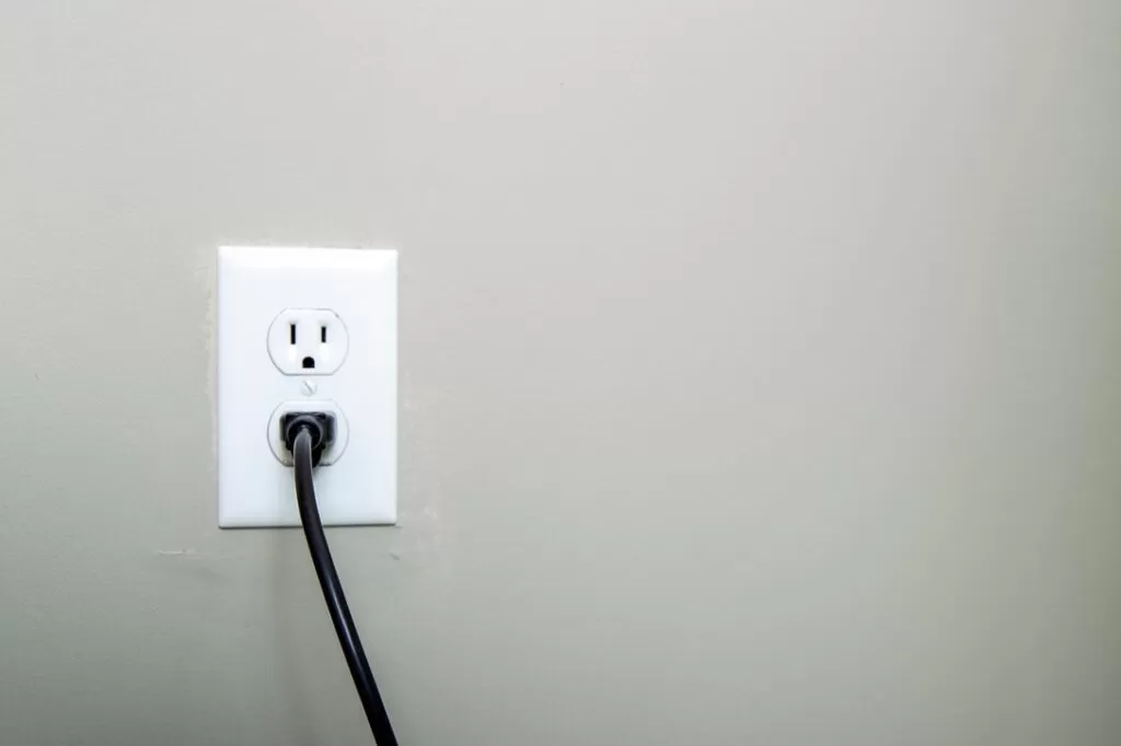 Black cord plugged into a white outlet
