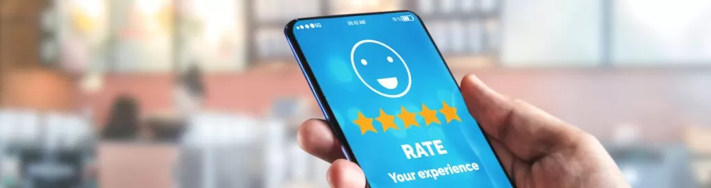 A close up image of a person holding a phone. On the screen is an app asking the homeowner to rate their experience.