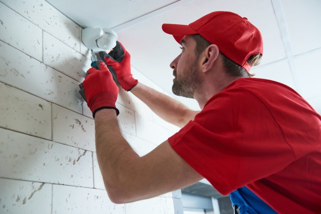 motion sensor or movement detector installation or adjustment by construction worker on the ceiling