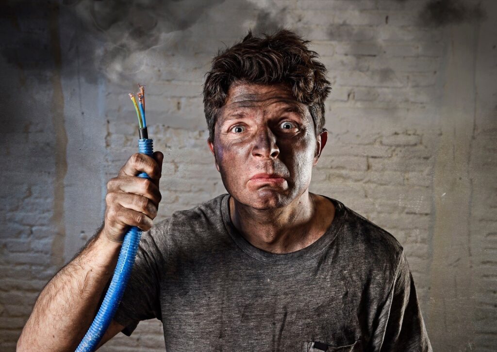 Singed man holding electrical wires to show unlicensed electrician work