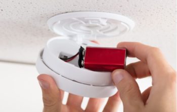 Close up of hand changing battery in smoke detector
