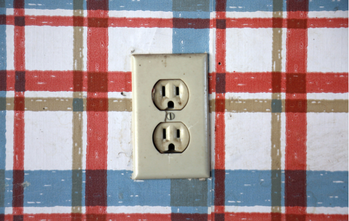 Old dangerous looking electrical outlet on a plaid wall