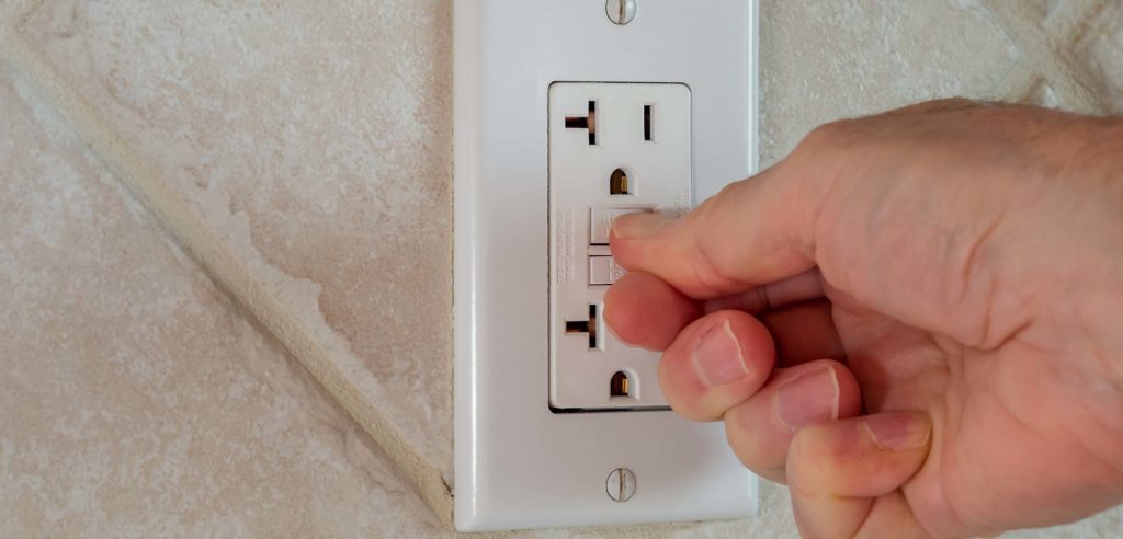 Hand pressing buttons on wall outlet.