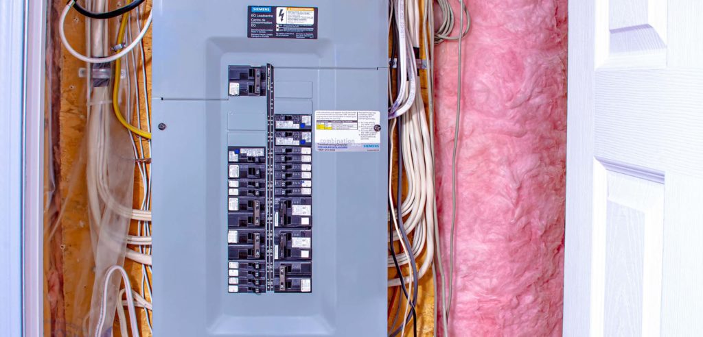 Main electrical panel in home, surrounded by fibreglass insulation.