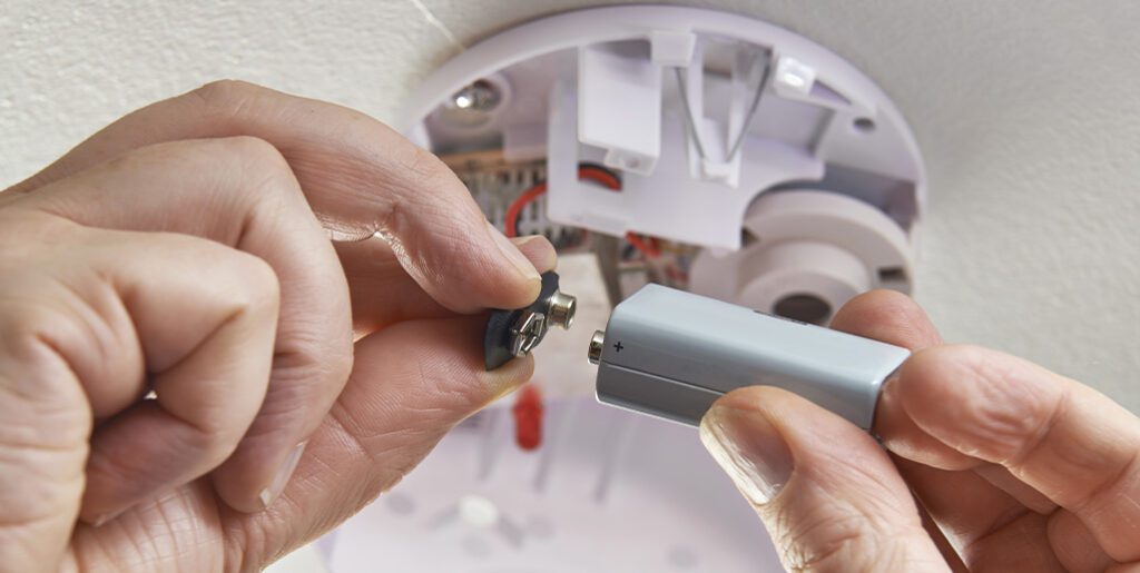 Person connecting battery to smoke alarm.