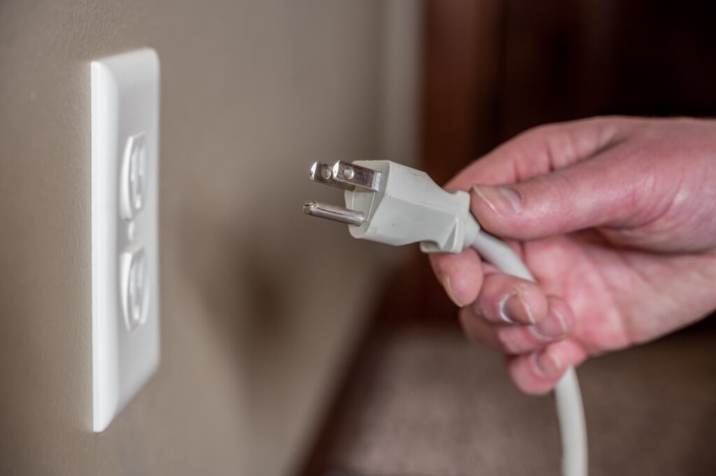 Homeowner about to plug device into faulty electrical outlet