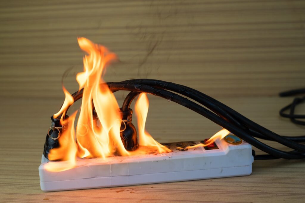 On fire multi socket with the connected power strip with a bunch of plugs on wood background