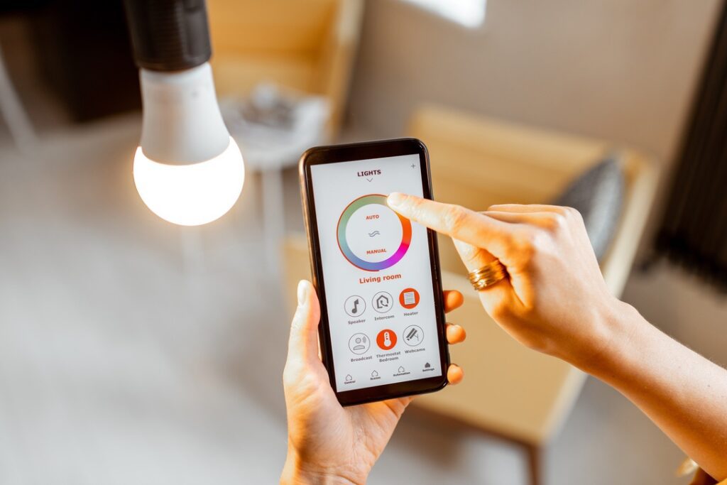 Controlling light bulb temperature and intensity with a smartphone application. Concept of a smart home and managing light with mobile devices