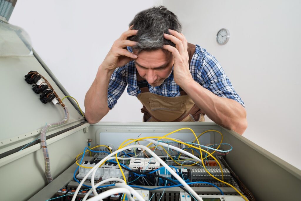 Portrait Of A Confused Electrician Looking At Fuse Box