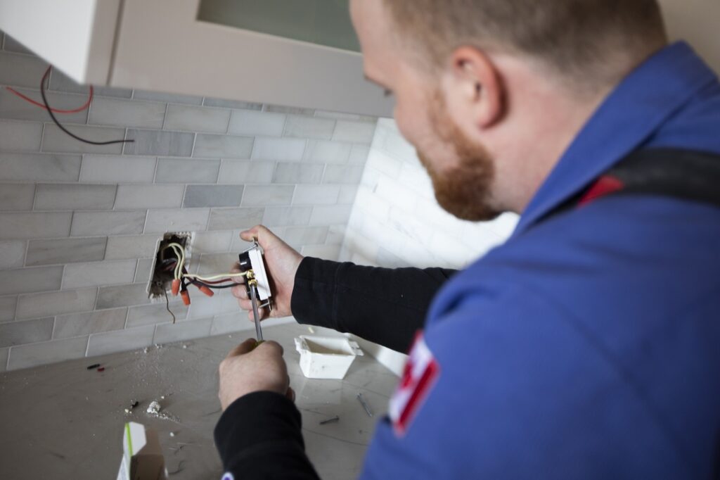 Electrician working on outlet in modern kitchen