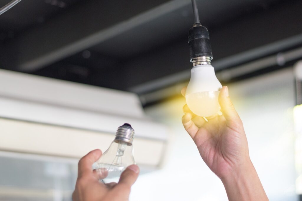 Person replacing old light bulb with LED version for extra security and convenience at home