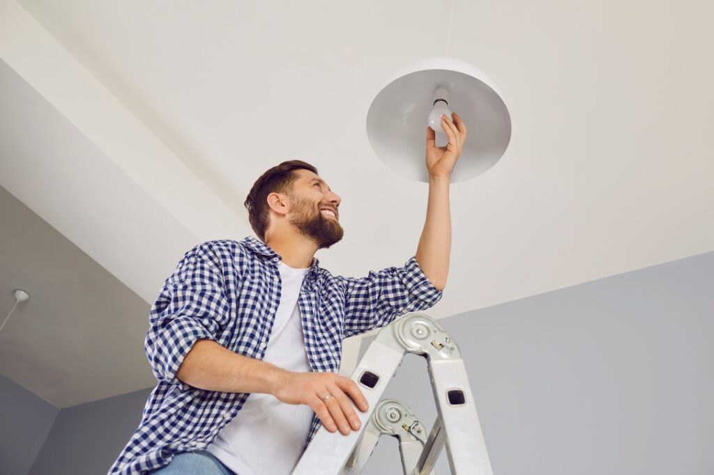 Man replacing light bulb in home