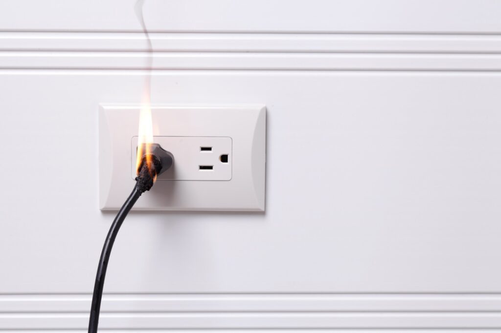 Outlet with smoke rising from flaming wire in electrical emergency