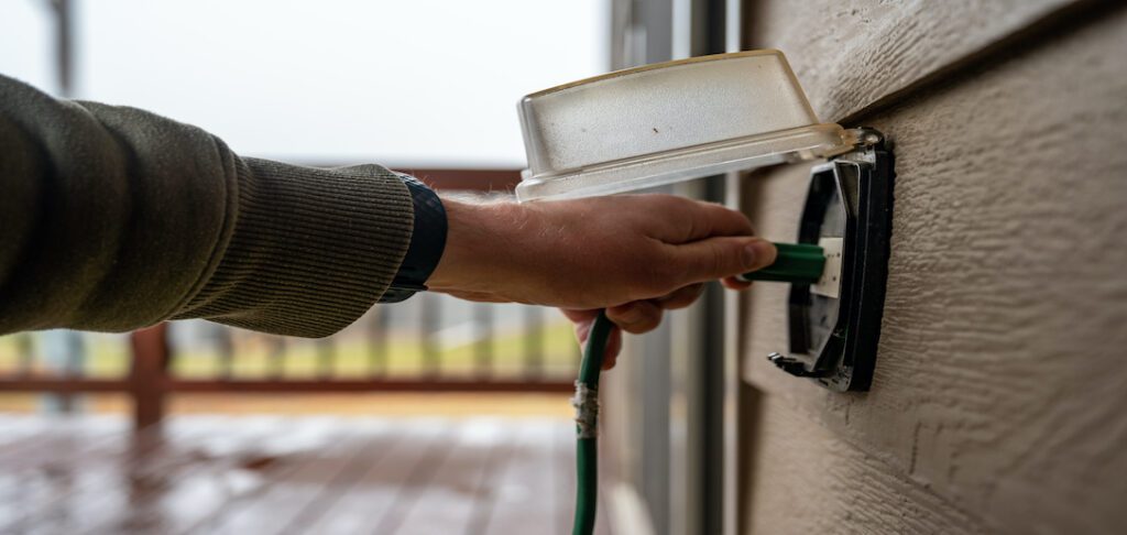 Person plugging an outdoor extension cord into a GFCI outlet